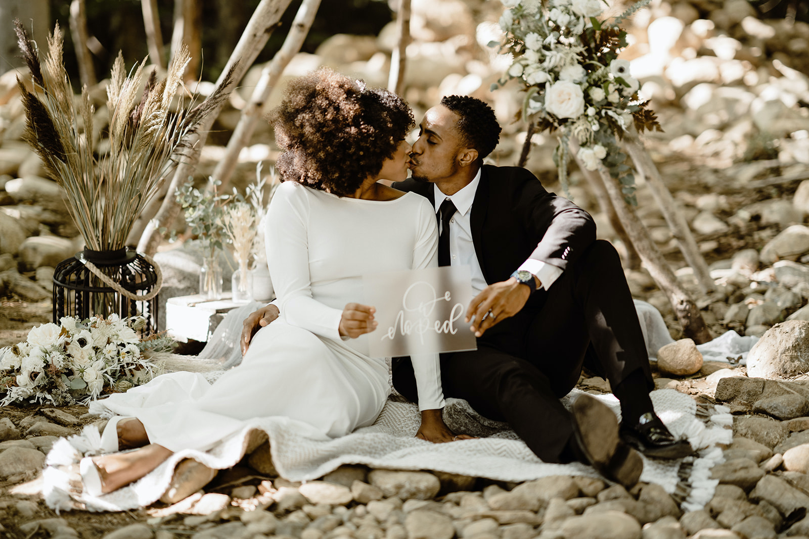 couple holding up a sign saying 'eloped' with a free-spirited bohemian backdrop
