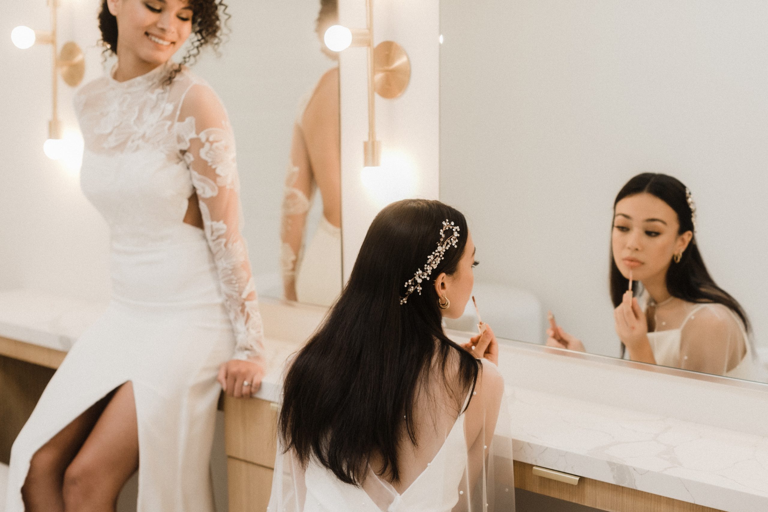 Two brides getting ready looking in a mirror
