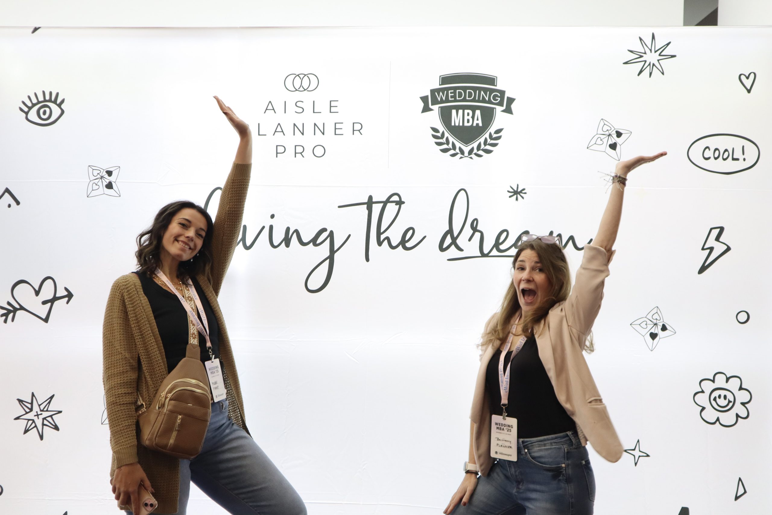 Two professional event planners smile and engage at the Wedding MBA convention booth, showcasing their support for Aisle Planner Pro as their preferred wedding management software and business suite.