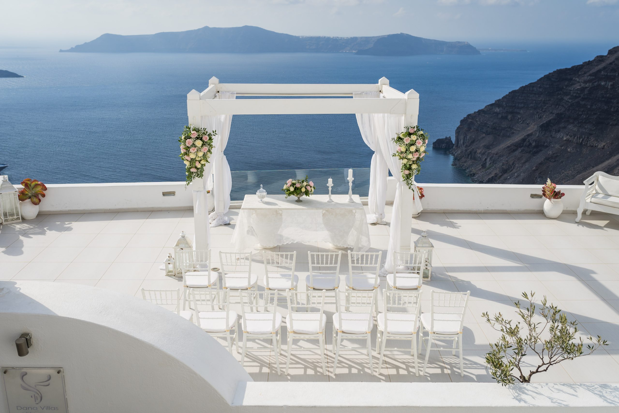 all white waterfront wedding ceremony setup in Santorini, Greece