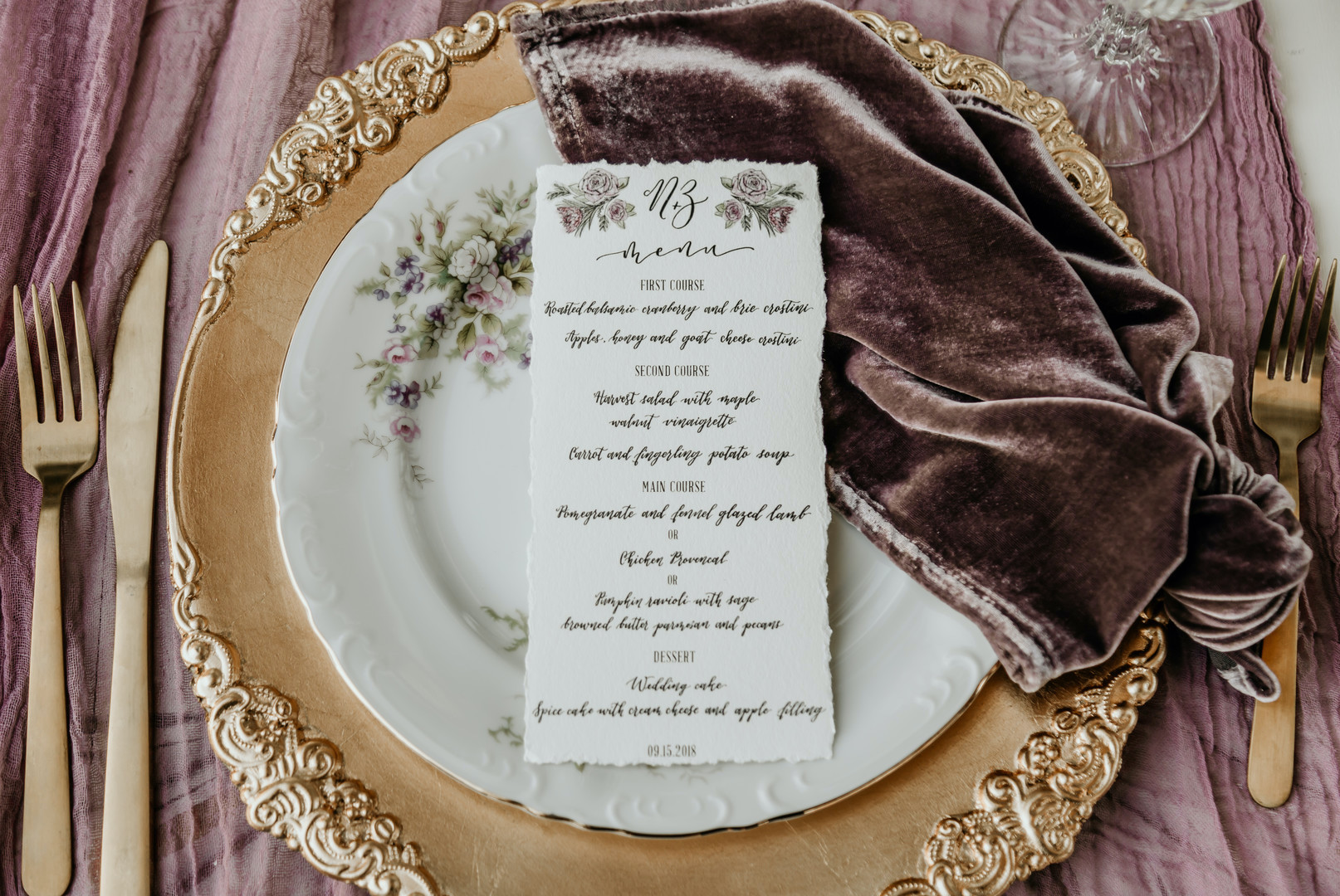 gold, white, and cream place setting with purple velvet cloth and gold utensils