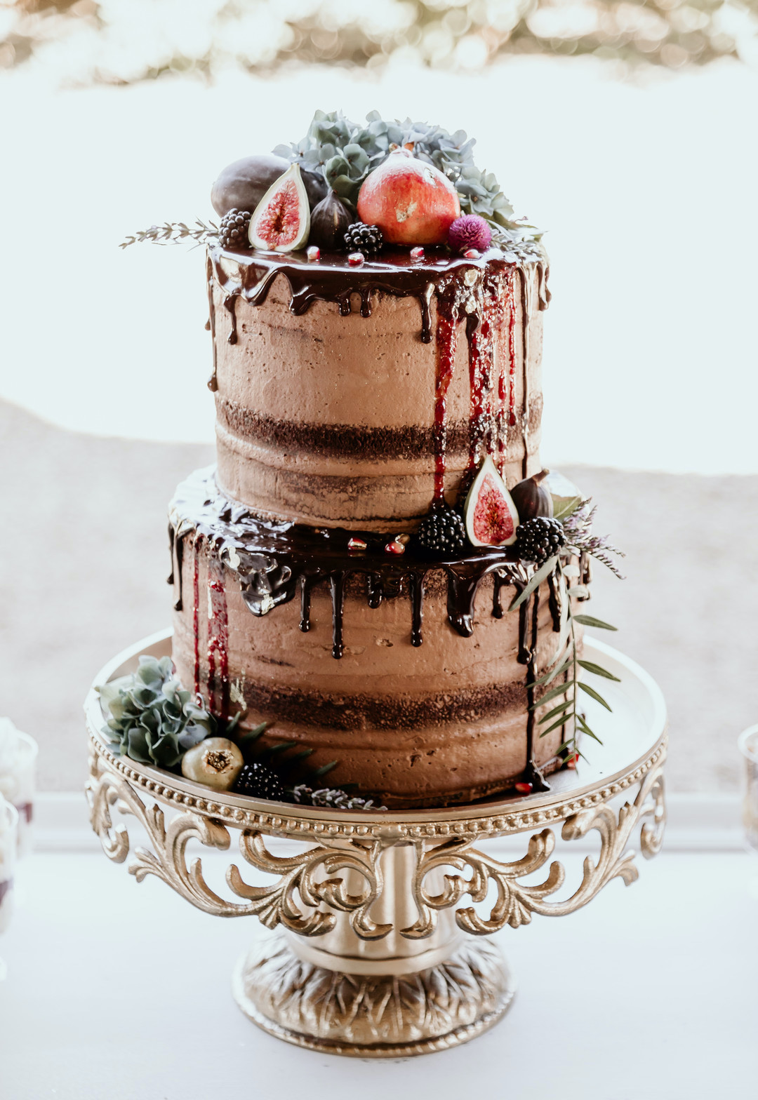 decadent chocolate cake on gold platter topped with pomegranates and berries