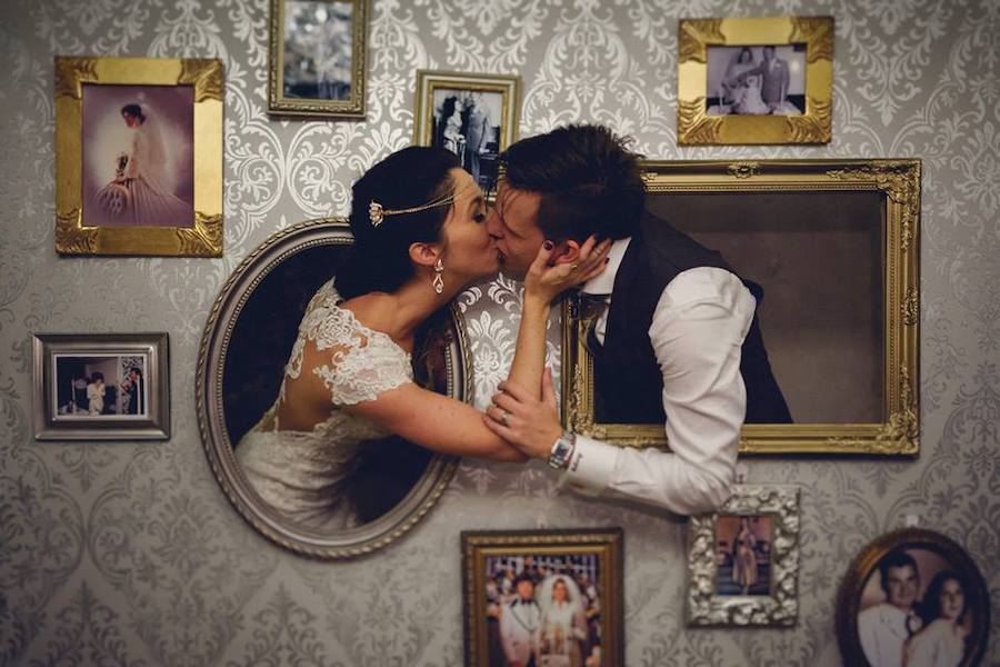 couple poking thier heads out of a photo wall kissing