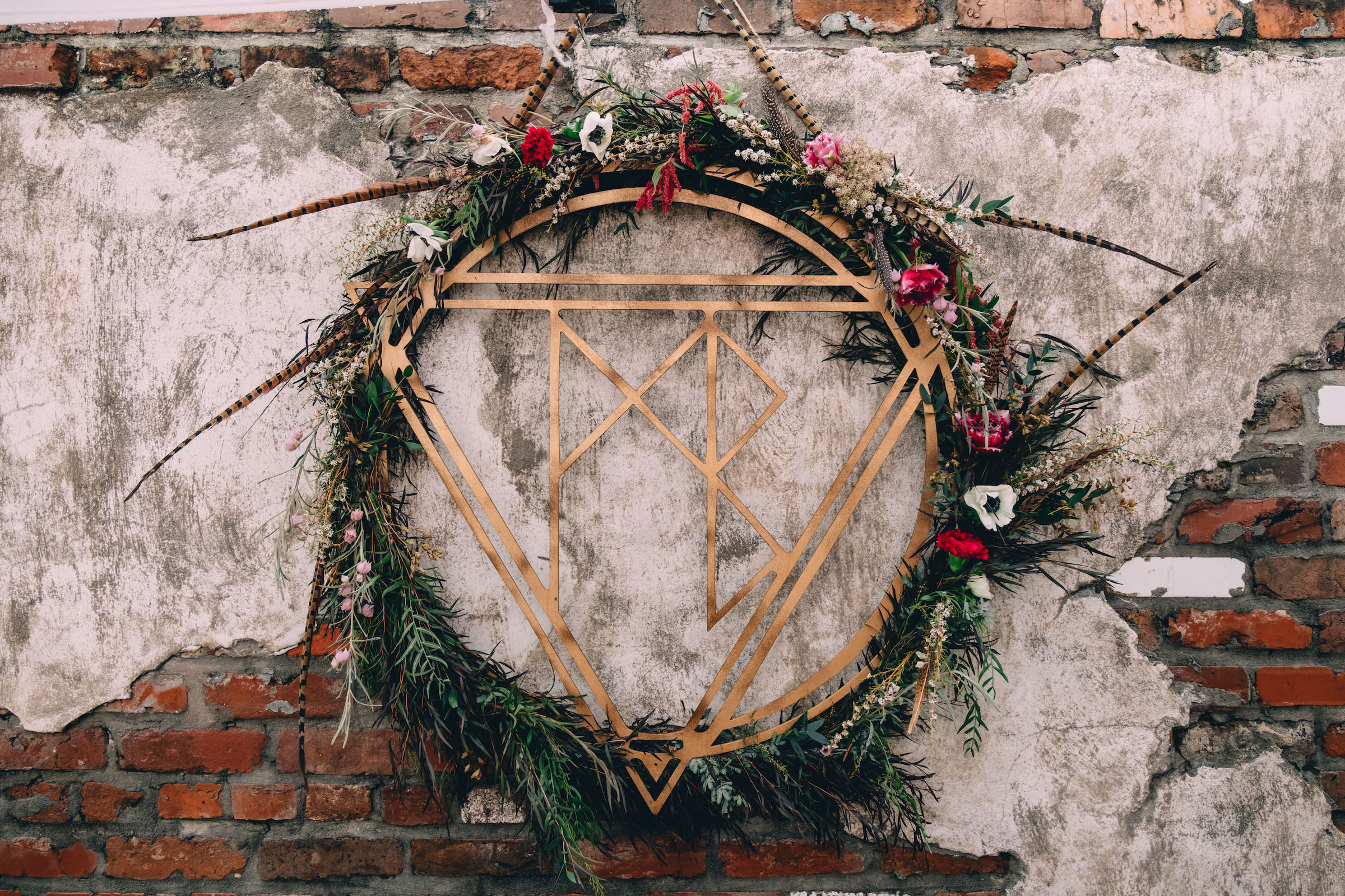 Alchemy Events metal logo in gold with circular green leaf at event