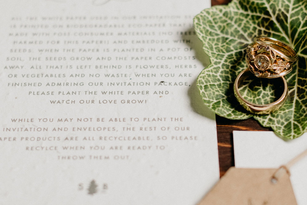 letter with leaf holding gold wedding rings