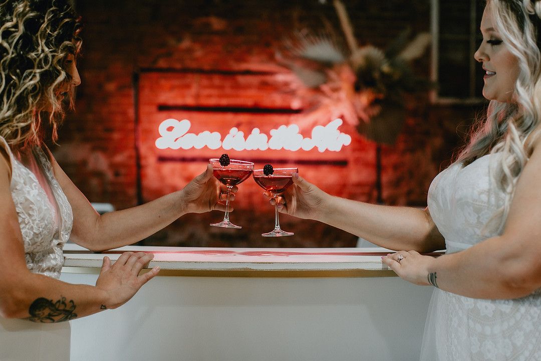 Brides cheersing in front of light up sign!