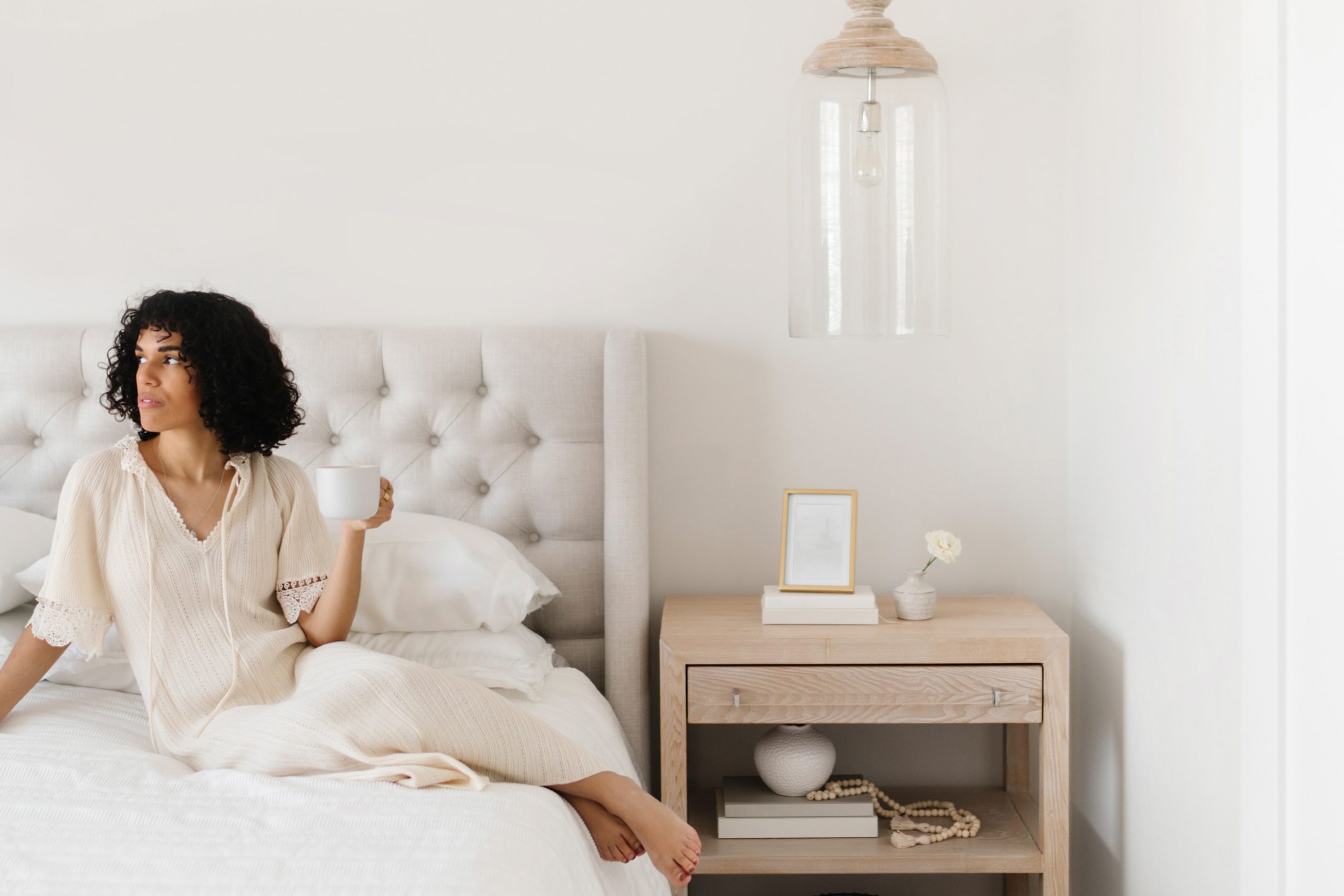 Woman sitting on bed holding cup of coffee