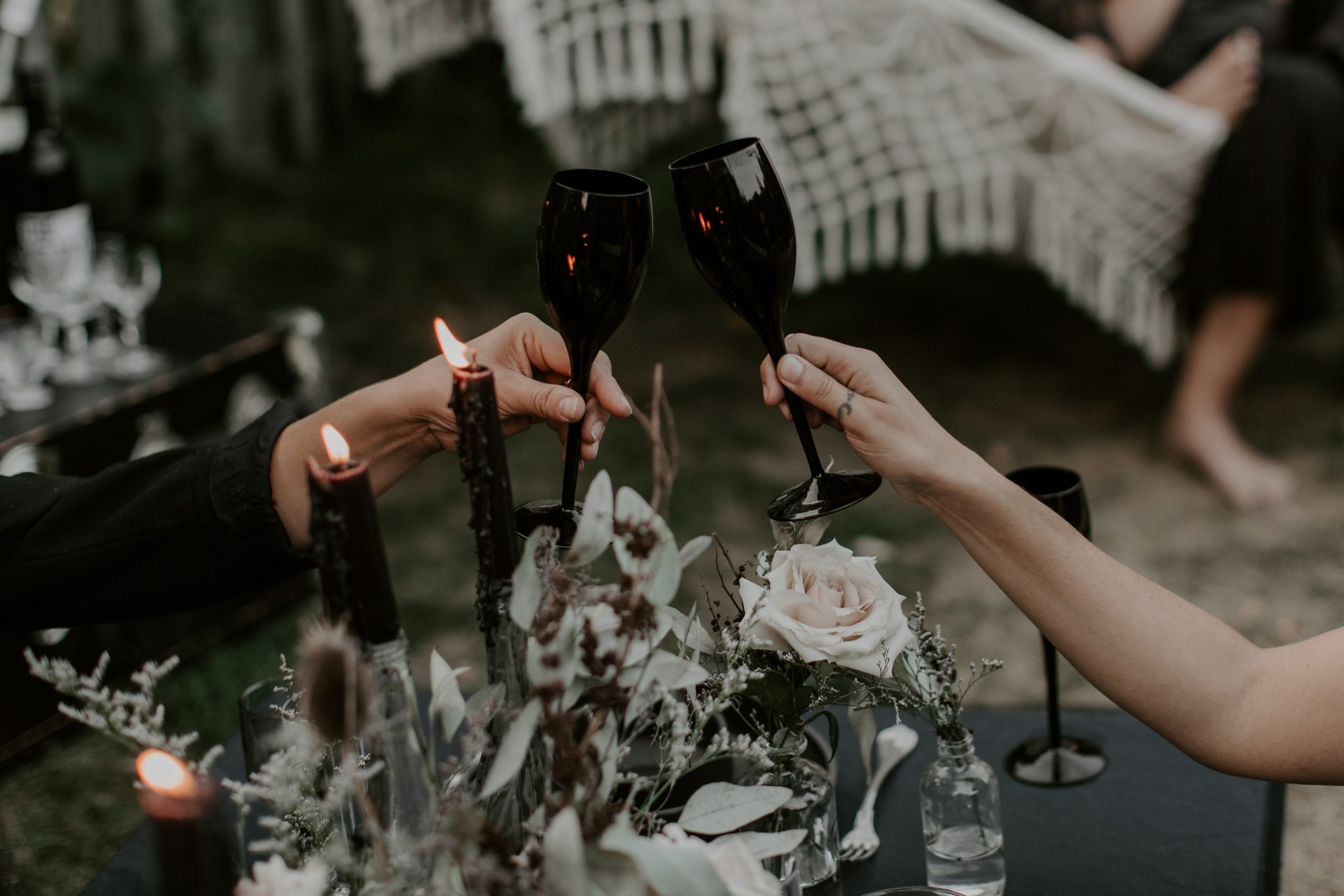 Two people cheering using black wine glasses